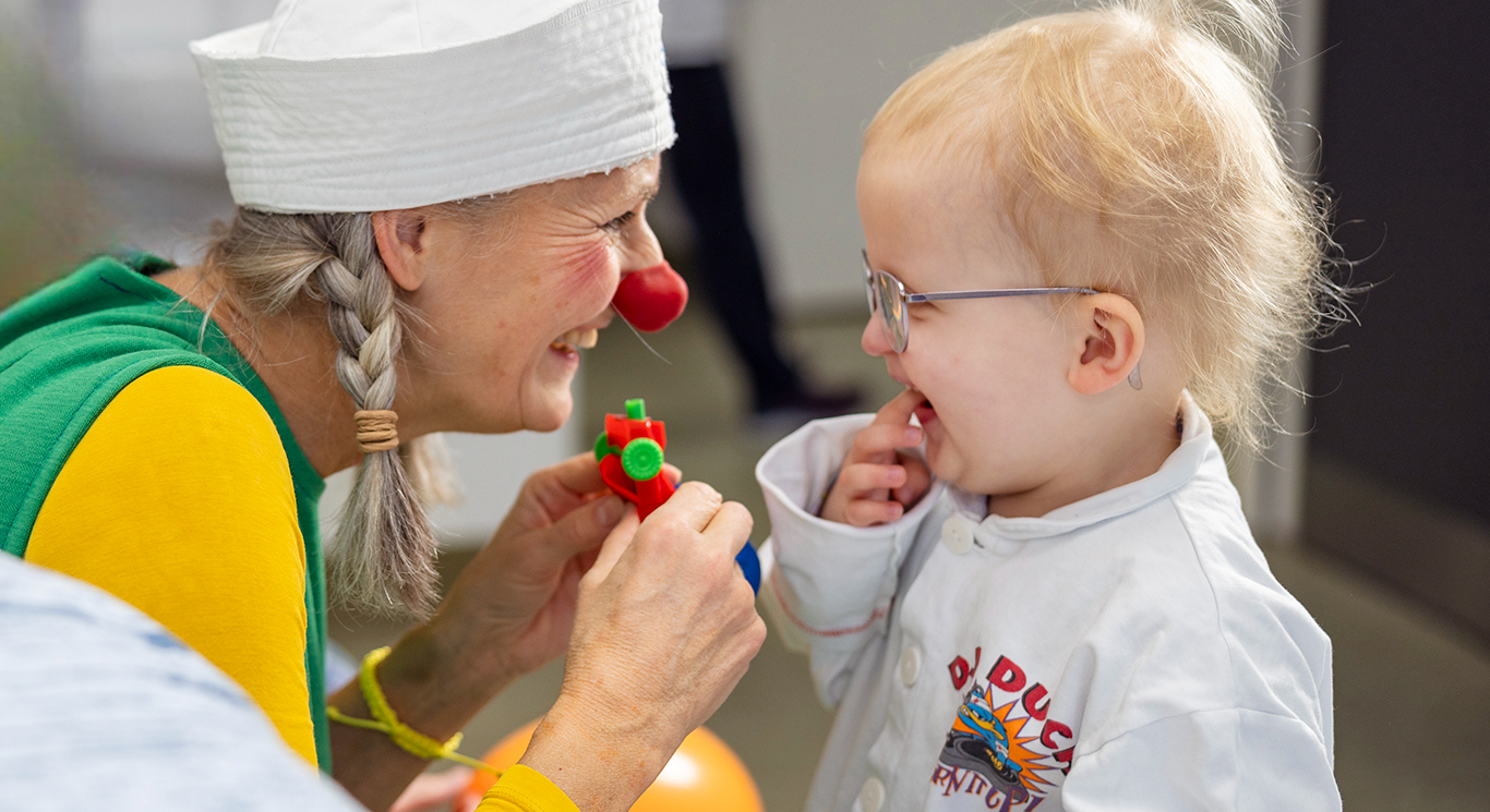 Hospitalsklovnen Petunia og lille Agnes ser på en lille figur og smiler til hinanden.
