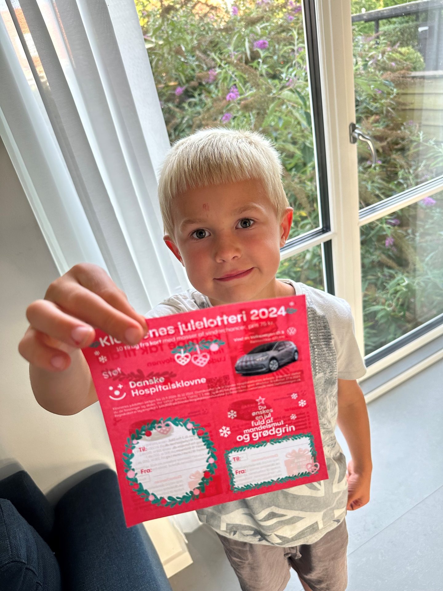 Charlie viser Julelotteriet fra 2024 frem i hånden.