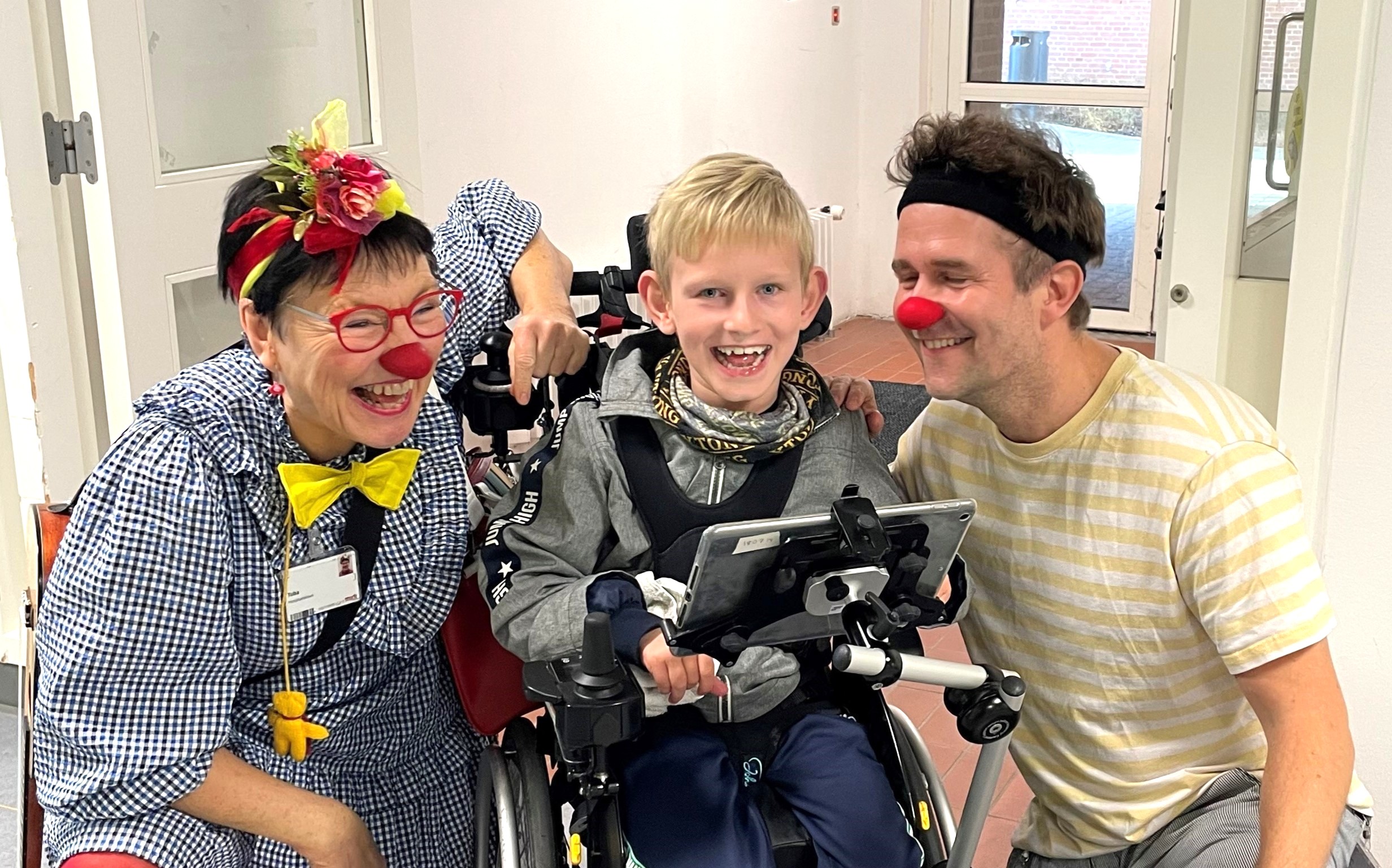 Walther sidder i sin kørestol omgivet af de to hospitalsklovne Tuba og Makaroni