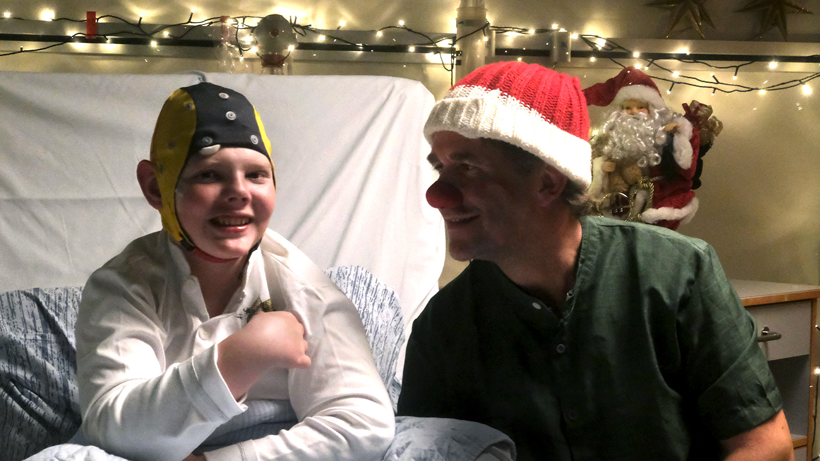 Kalle og hospitalsklovnen Makaroni sidder ved siden af hinanden på en hospitalsstue