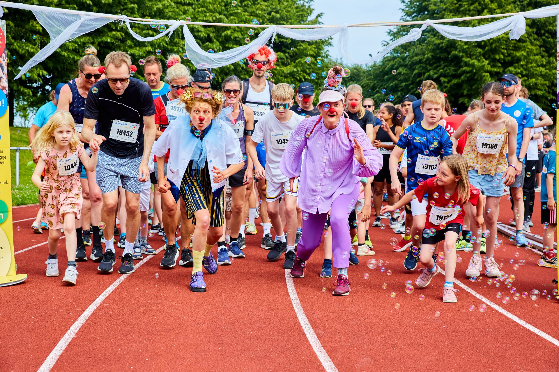 En masse klovneløbere og de hospitalsklovne løber fra målstregen til et klovneløb.