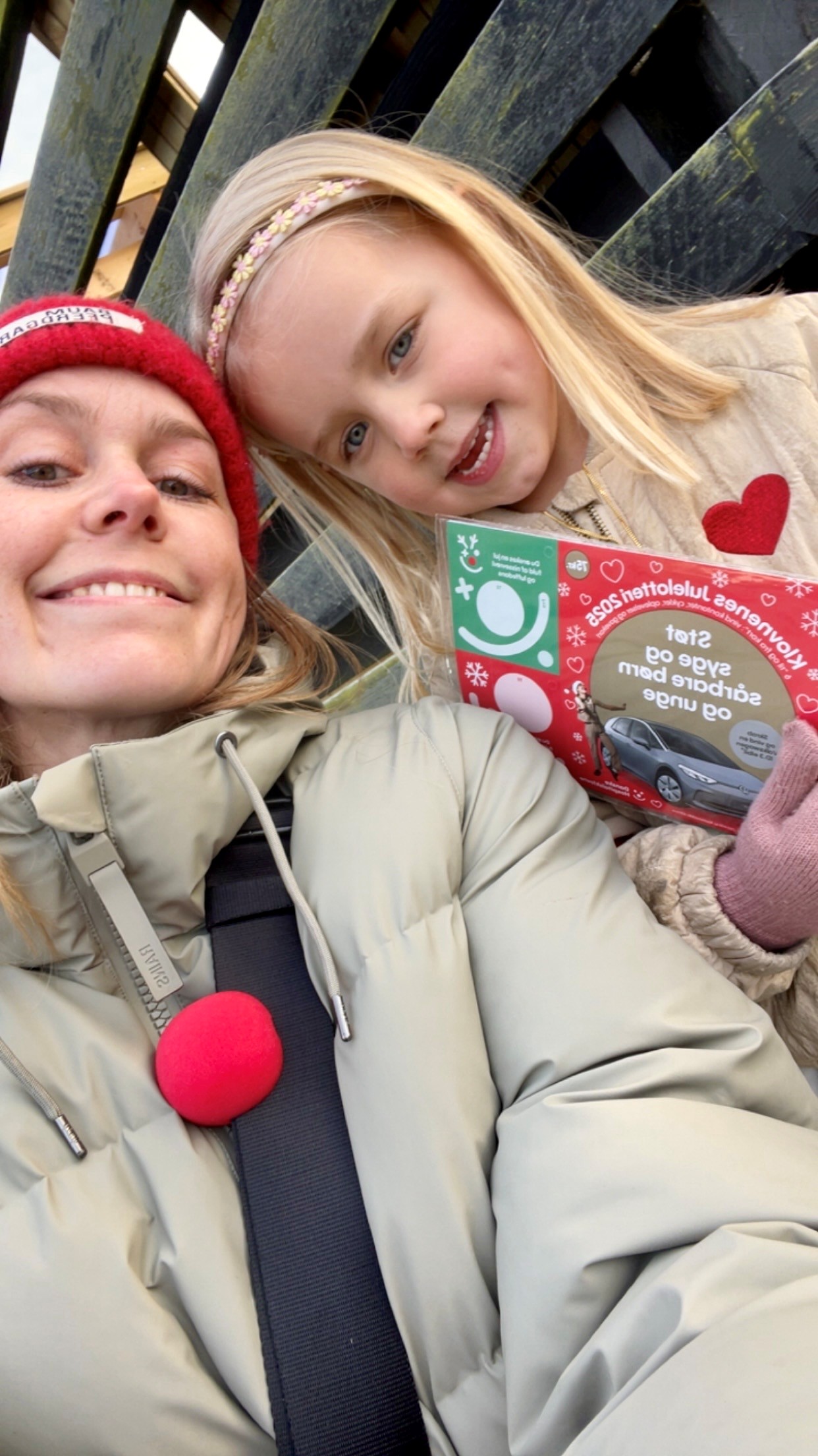Mor Josefine sidder sammen med datteren, Marta. De er ude at sælge Klovnenes Julelotteri og Marta viser det frem.