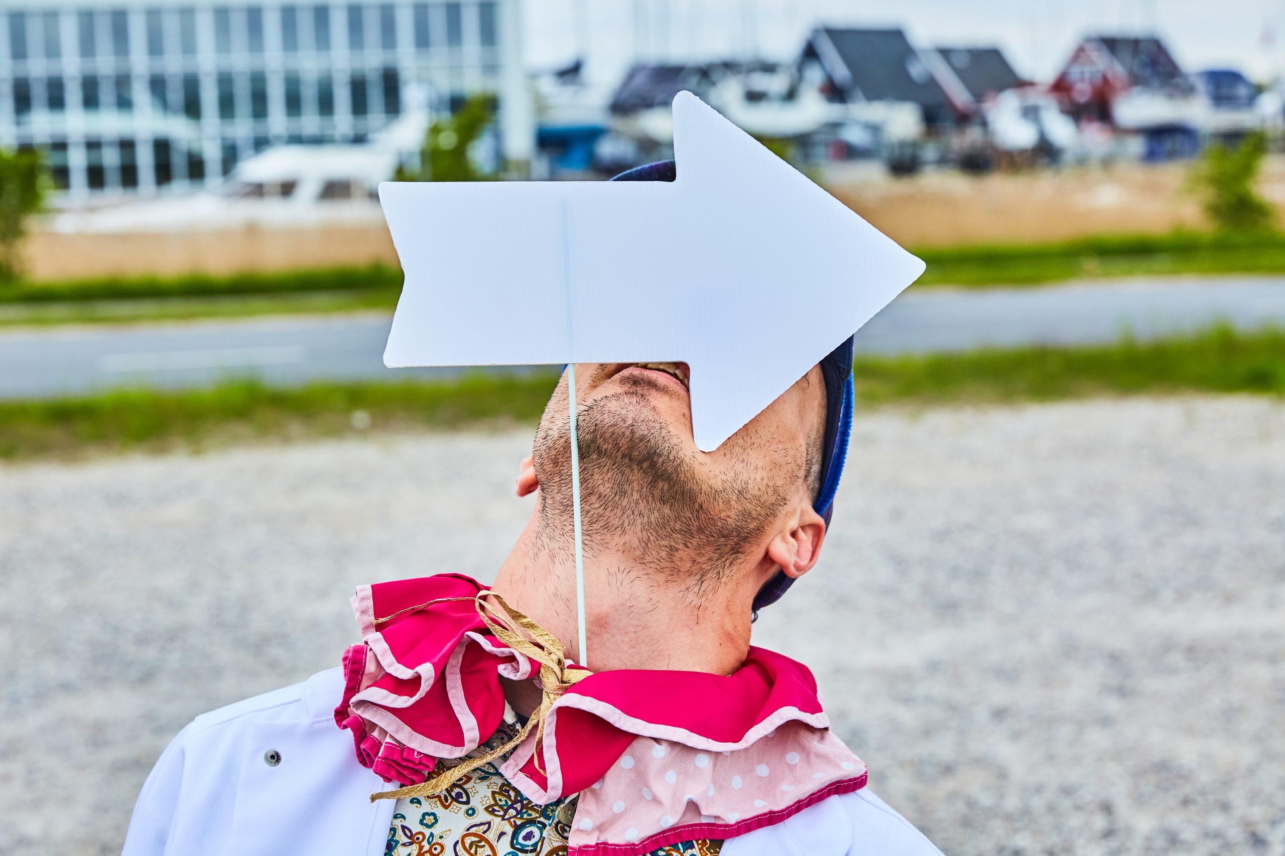 Pernille og Sidney hænger plakater op til Klovneløb. De står foran en rød mur og smiler til hinanden, mens de hænger en gul plakat op.