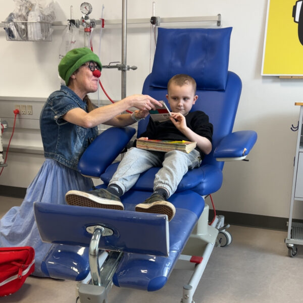 Cebastian og hospitalsklovnen Luna sidder sammen på en hospitalsstue